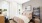 A sophisticated bedroom featuring a plush bed with neutral bedding, abstract wall art, bedside lamps, and a large closet leading to a private bathroom.