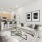 A stylish living room with a neutral-toned sofa, sleek furniture, and a cozy atmosphere, complemented by a modern kitchen with bar seating and stainless steel appliances.