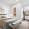 A stylish bedroom featuring a plush upholstered bed, soft earth-toned bedding, abstract wall art, and large windows with views of a brick building.
