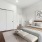 A modern bedroom with a neutral color palette, featuring a comfortable bed with textured bedding, bedside lamps, minimalist decor, and a large closet with sliding doors.