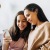 a couple of women sitting on a couch looking at a phone